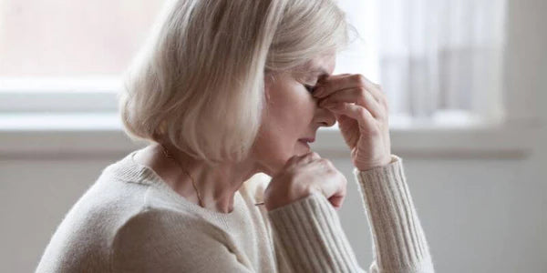 donna in menopausa che manifesta stanchezza con una mano sulla fronte